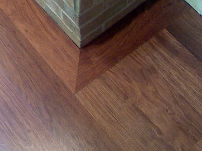 A detail of a wide-width Brazilian Cherry (Jatoba) hardwood floor picture frame around a brick hearth in Coralville